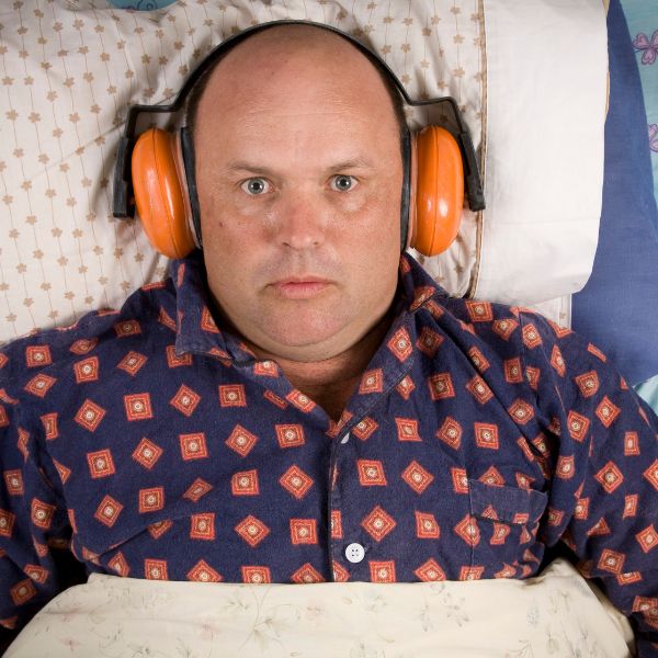 A man in bed wearing noise cancelling headphones